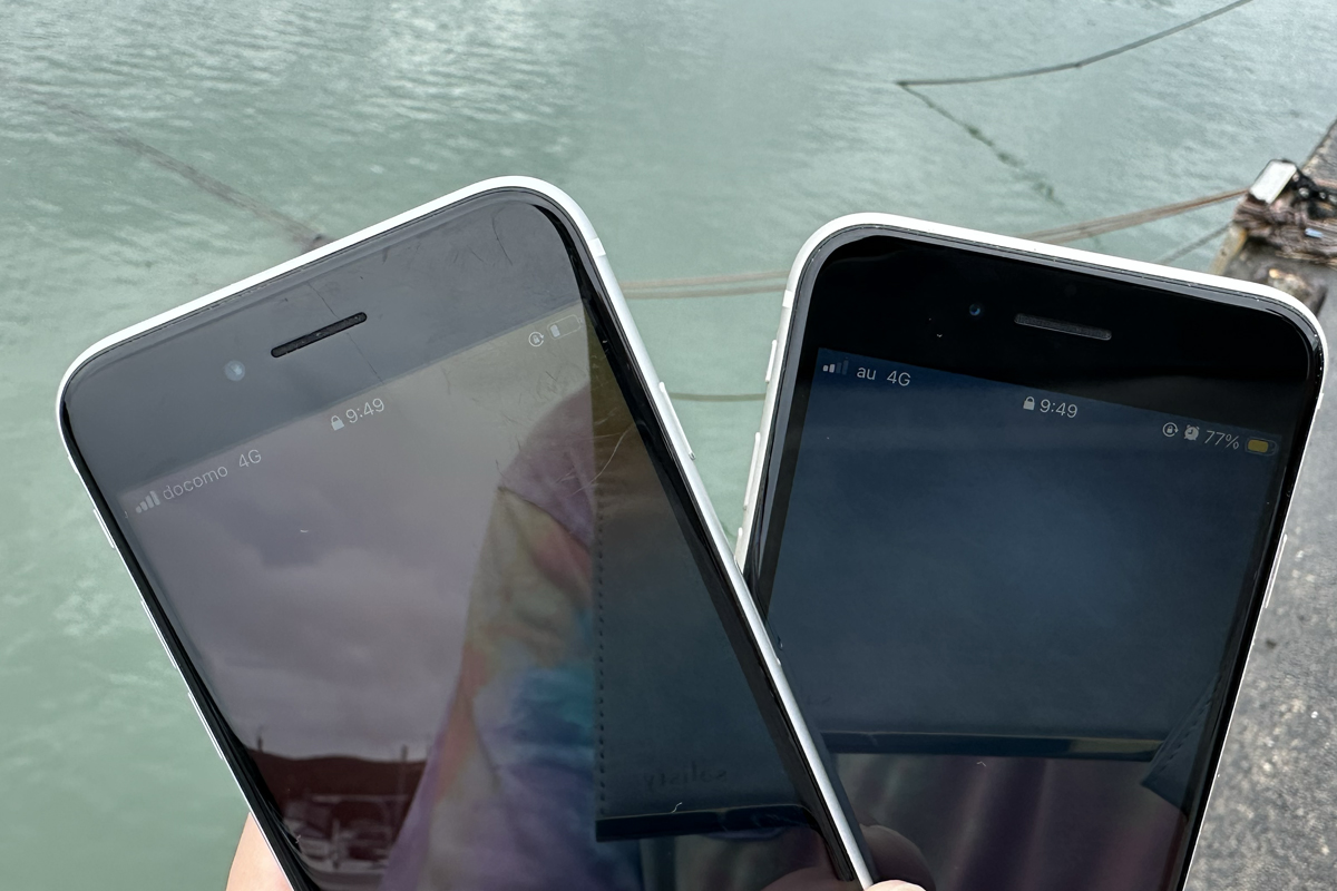 海辺でahamo（左・docomo 4G 4本）とpovo（右・au 4G 2本）のアンテナ本数を並べて撮影